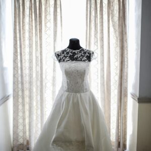 A beautiful bridal gown displayed on a mannequin, illuminated by natural light from a window.